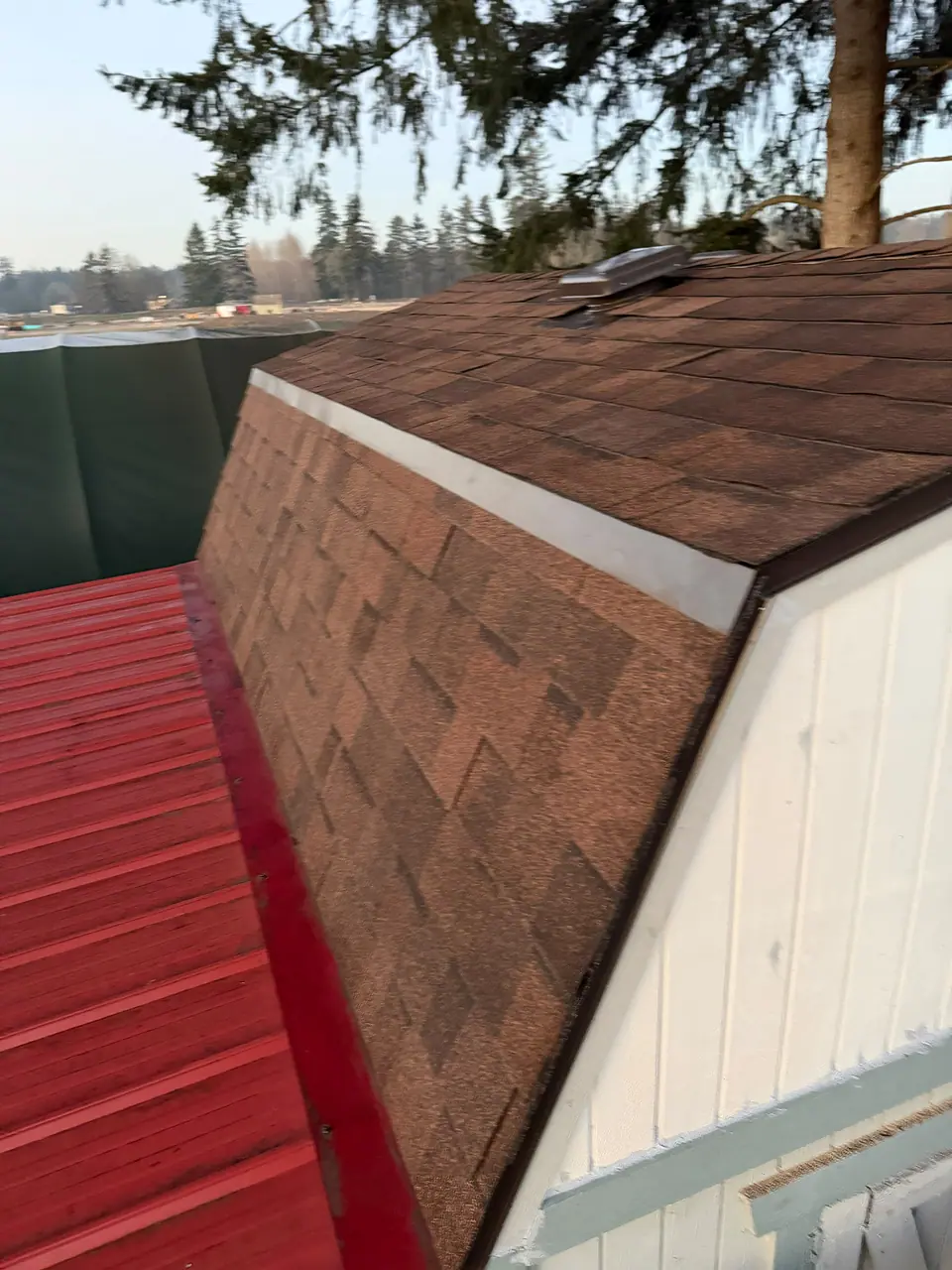 Brown shingles next to a red metal roof